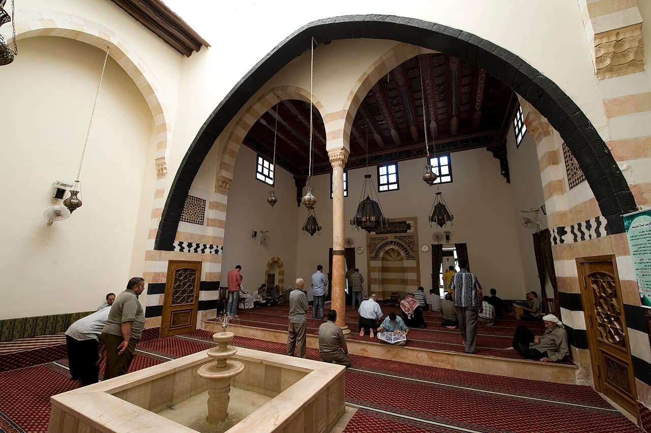 Tarihî bir caminin kemerli ve halı kaplı iç mekânı