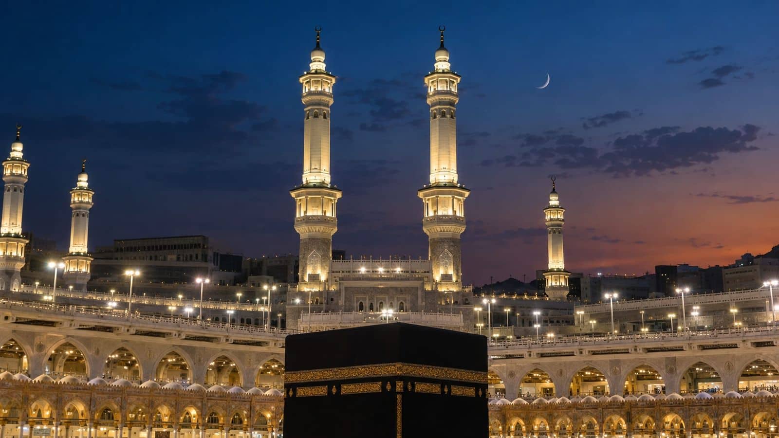 Alacakaranlıkta ışıklandırılmış Mescid-i Haram minareleri, hilal ve önde Kâbe