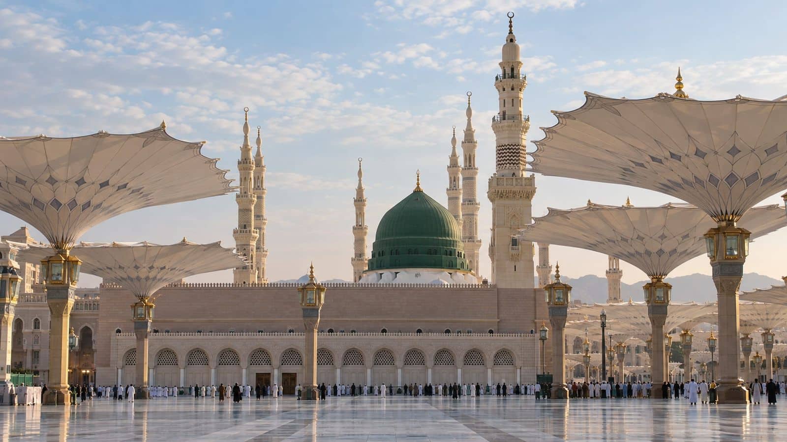 Mescid-i Nebevî'nin yeşil kubbesi ve minareleri, avludaki açık şemsiyelerle